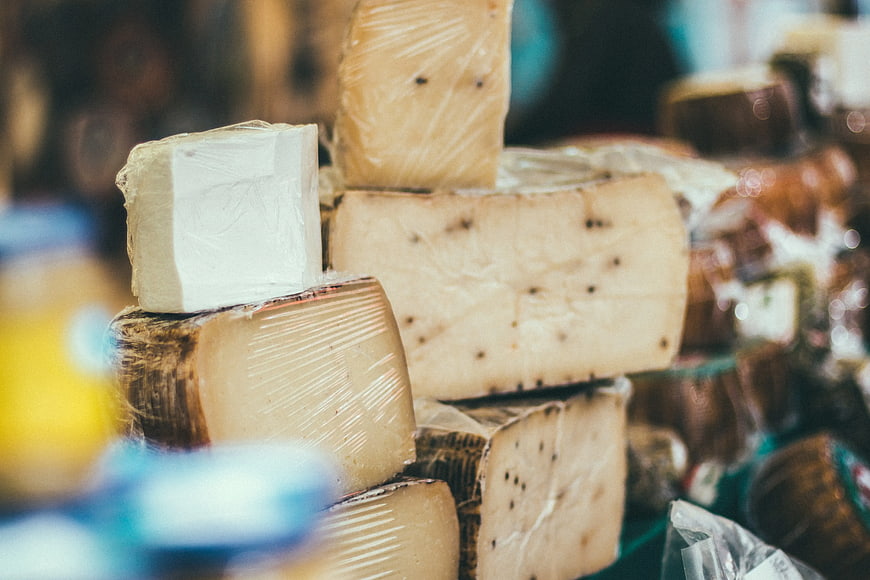 Assorted artisanal cheese wheels wrapped in plastic