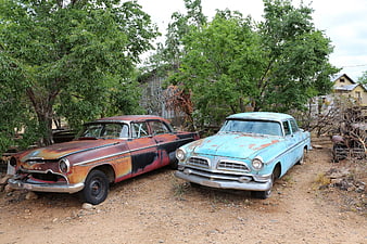 Two vintage American cars in a junkyard