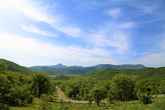 Winding Road Through Green Valley and Mountains