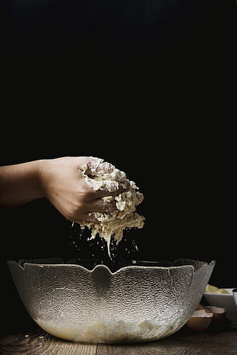 Hand kneading dough in a textured glass bowl
