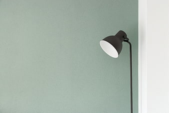 Minimalist black floor lamp against sage green wall