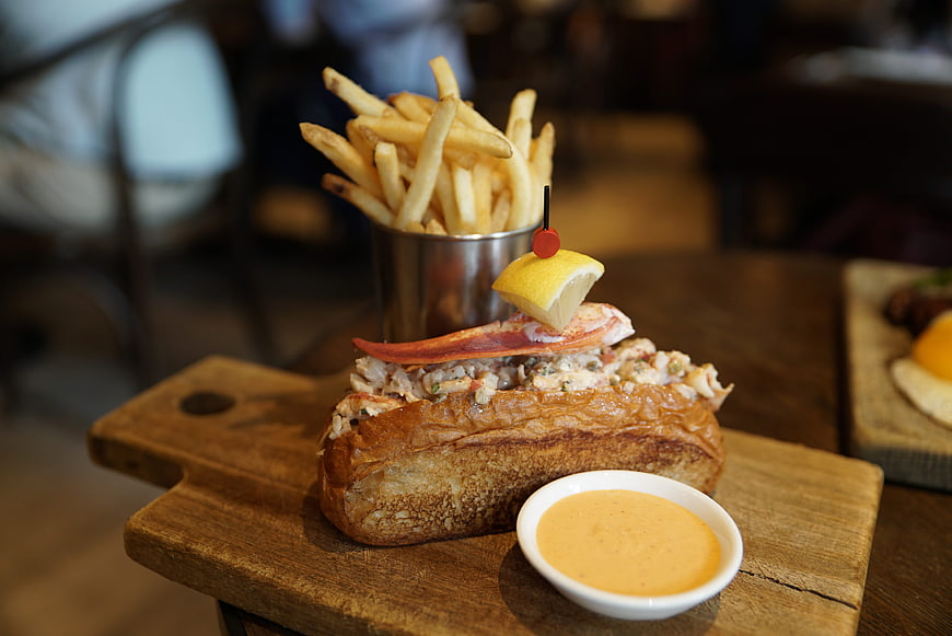 Gourmet Lobster Roll Sandwich With French Fries And Aioli On Wooden Board
