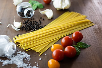 Uncooked spaghetti with tomatoes, garlic, and spices on wood