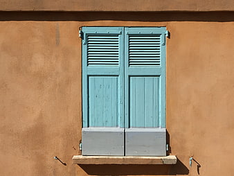 Blue wooden shutters on a textured orange stucco wall