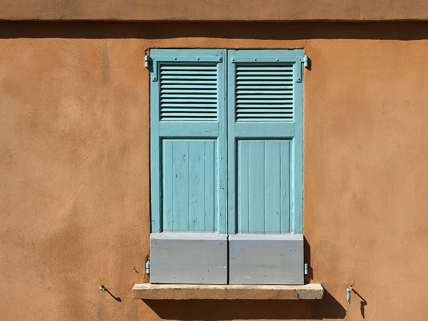 Blue wooden shutters on a textured orange stucco wall