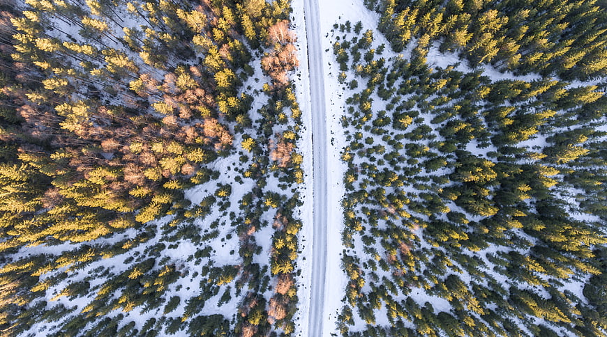 Aerial View of Snowy Forest Road in Winter