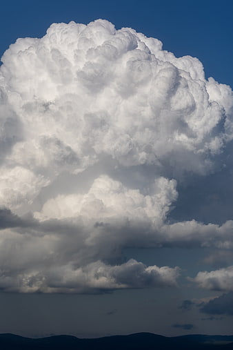 Massive white cumulus cloud formation against deep blue sky