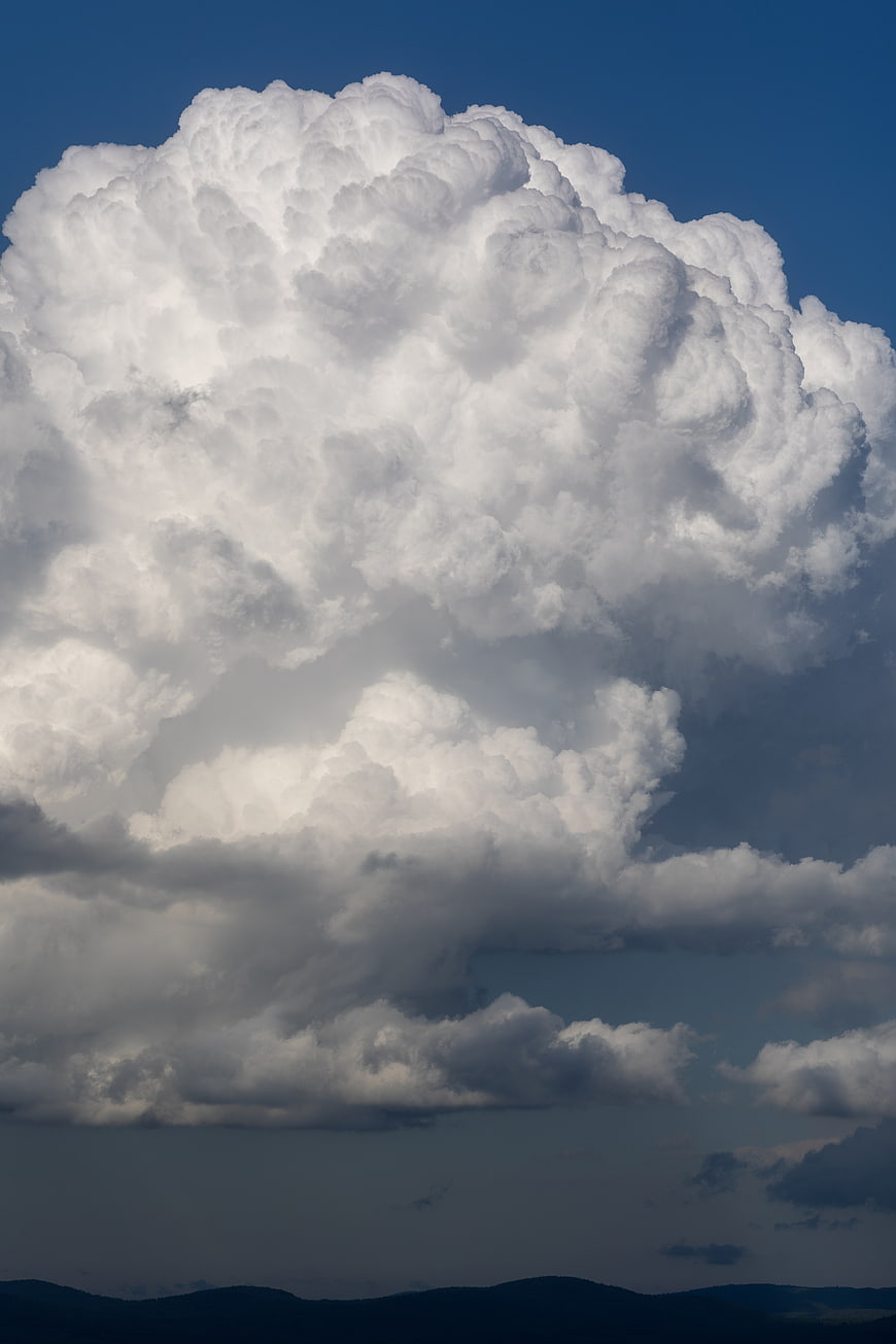 Massive white cumulus cloud formation against deep blue sky