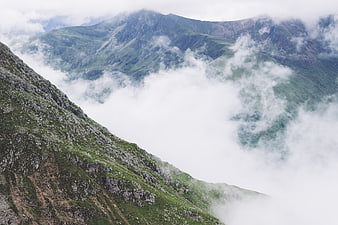 Misty Mountain Peaks with Green Slopes and Clouds