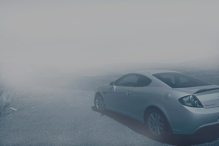 Silver sports coupe parked on foggy road