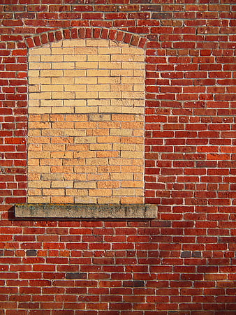 Brick wall with bricked-up arched window and stone sill