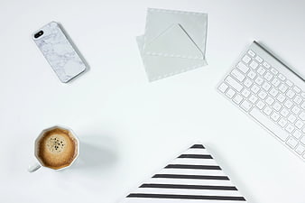 Minimalist white desk workspace with coffee and keyboard