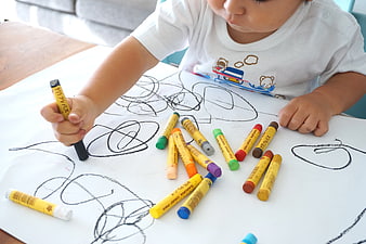 Toddler drawing with crayons on white paper