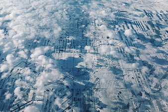 Aerial view of snow-covered fields through scattered clouds