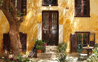 Old Yellow House Facade with Wooden Shutters and Tree