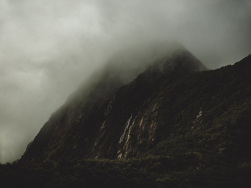 Misty Mountain Peak with Waterfall in Foggy Forest