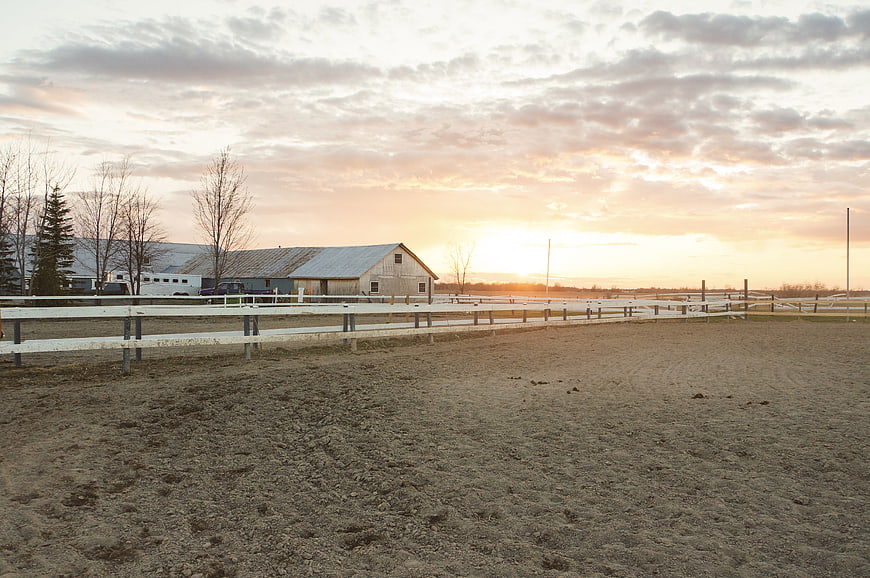 Rural horse farm with white fences at sunset