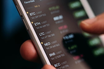 Close-up of hand holding smartphone displaying cryptocurrency trading app