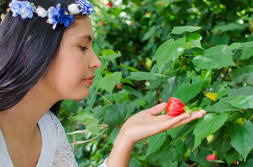 Young Woman with Flower Crown Smelling Red Hibiscus Bud