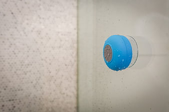 Blue Waterproof Bluetooth Speaker on Wet Glass Shower Wall