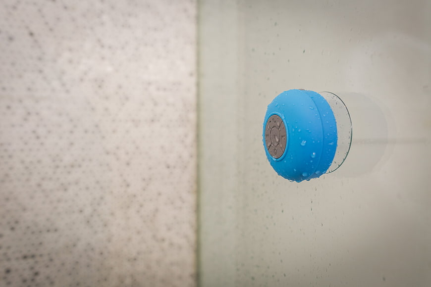 Blue Waterproof Bluetooth Speaker on Wet Glass Shower Wall