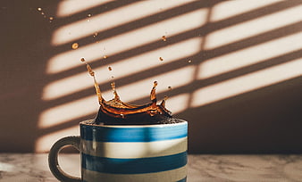 Coffee splash in striped mug with sunlight shadows