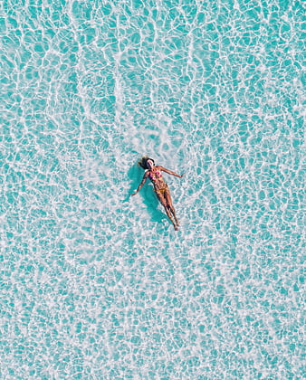 Aerial View of Woman Floating in Turquoise Ocean Water