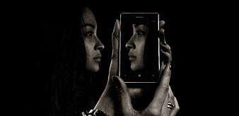 Woman holding smartphone with self-portrait on screen