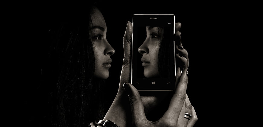 Woman holding smartphone with self-portrait on screen