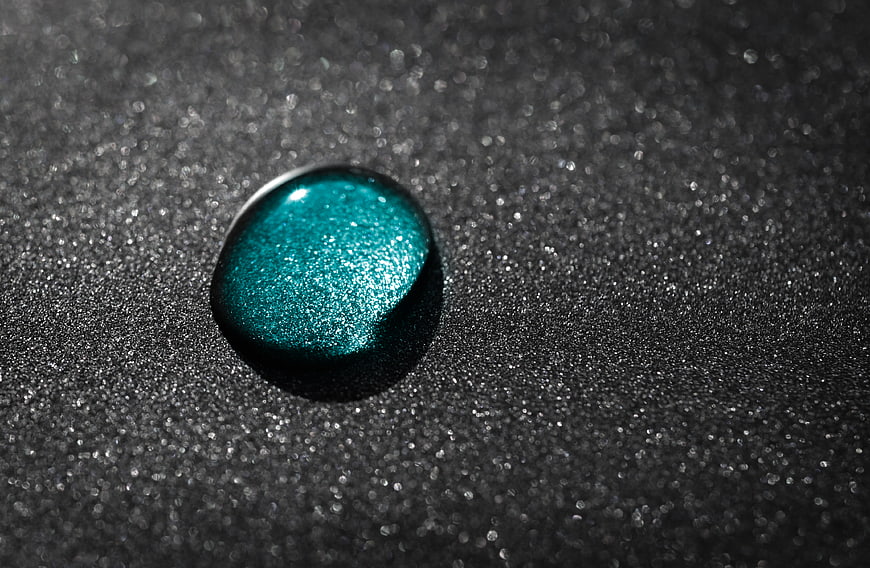 Shimmering Teal Glitter Drop on Dark Textured Background
