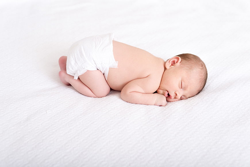 Sleeping newborn baby on white textured blanket