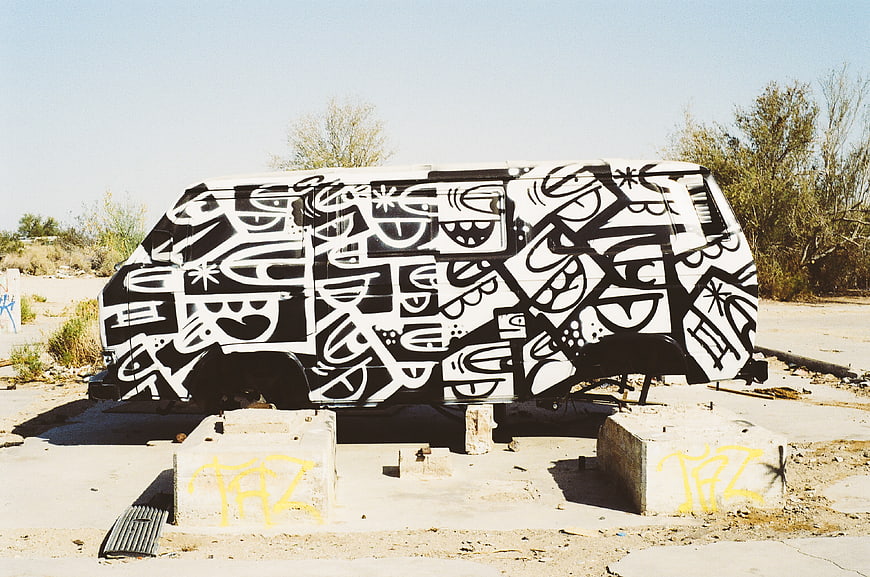 Abandoned Van with Black and White Graffiti Art in Desert