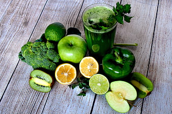 Green vegetable smoothie with fresh broccoli, apple, kiwi, and citrus on rustic wood