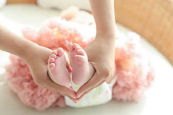 Mother holding baby feet in heart shape
