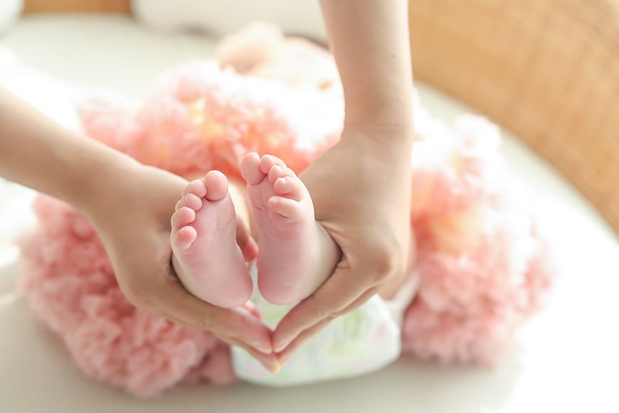 Mother holding baby feet in heart shape