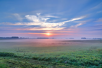 Misty Sunrise Over Green Meadow with Dramatic Clouds