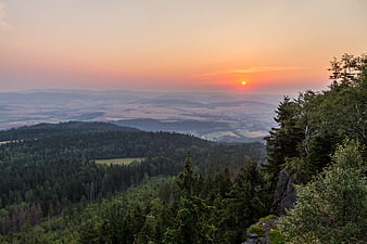 Sunset Over Rolling Hills and Forested Landscape