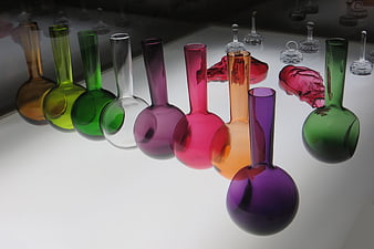 Colorful glass laboratory flasks on white surface