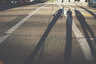 Long shadows of people crossing a street intersection