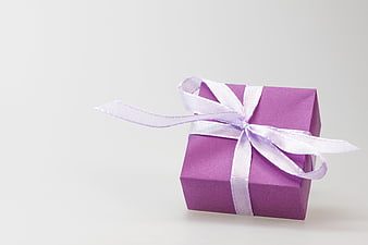 Purple gift box with white ribbon on white background