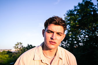 Young man with freckles looking at camera outdoors