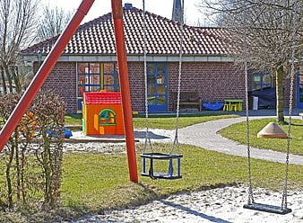Empty Kindergarten Playground with Swings and Playhouse