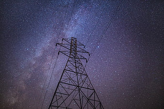 Silhouette of electricity pylon against Milky Way night sky