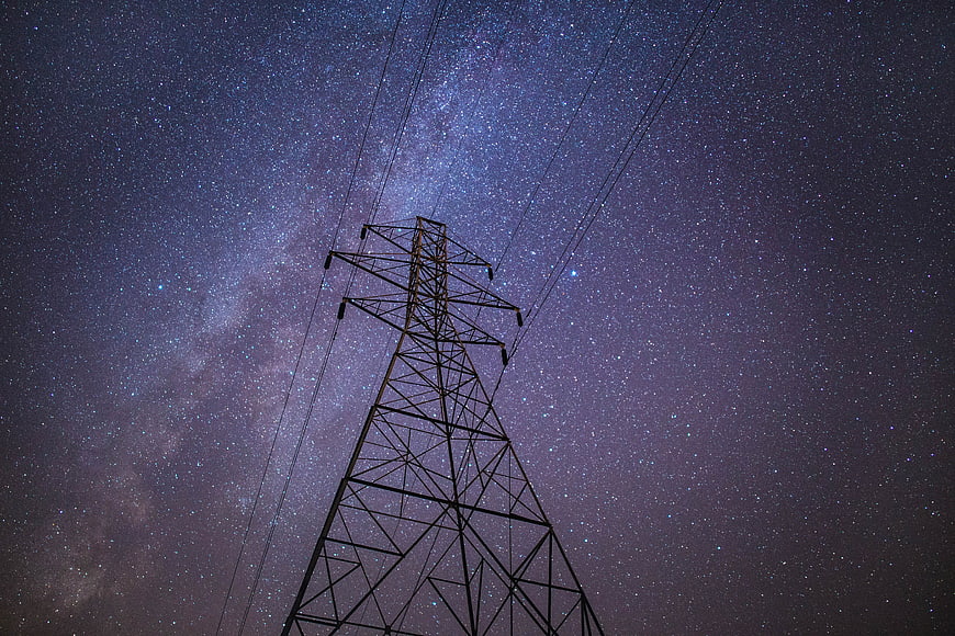 Silhouette of electricity pylon against Milky Way night sky