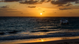 Fishing boat on ocean waves during golden sunset