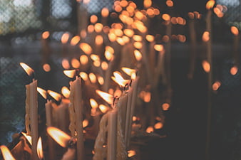 Rows of burning prayer candles with glowing bokeh background
