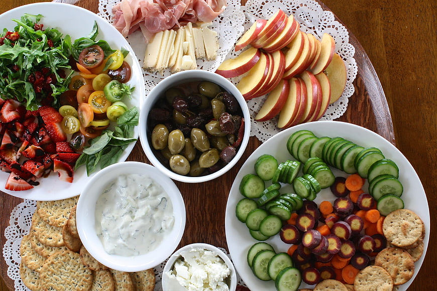 Overhead view of gourmet charcuterie board with cheese, fruit, and vegetables
