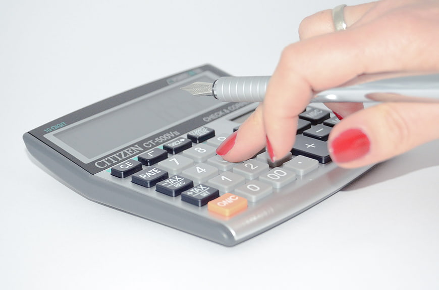 Woman's hand using calculator and pen for financial calculations