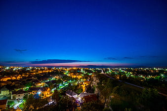 Night cityscape with glowing lights and starry blue sky