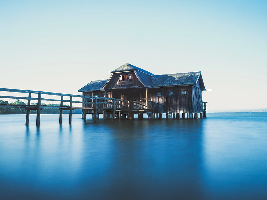 Serene wooden boathouse on stilts over calm blue water